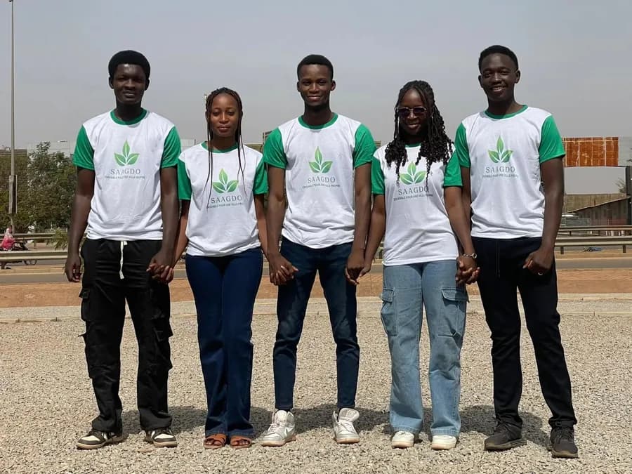 Cinq jeunes de l’équipe SAAGDO se tiennent la main, en t-shirts « SAAGDO — Ensemble pour une ville propre »